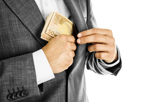 A Businessman In A Suit Putting Money In His Pocket