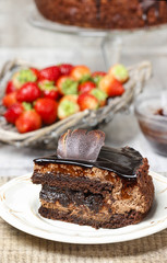 Chocolate cake and basket of fresh raw strawberries in the backg