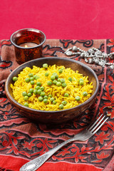 Indian cuisine: bowl of yellow rice with green peas on red backg