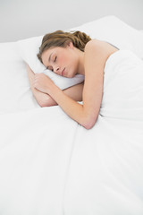 Lovely sleeping woman lying under the cover on her white bed