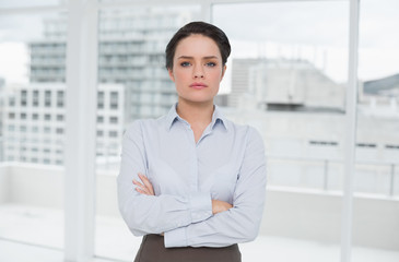 Elegant businesswoman standing with arms crossed in office