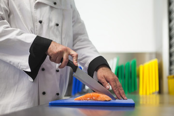 Fototapeta na wymiar Chef cutting salmon with sharp knife