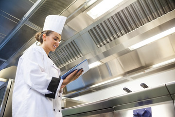 Young cheerful chef using tablet