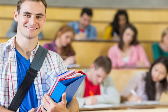 Smiling male with students sitting at lecture hall