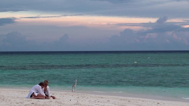 Two girls at the beach watching for the gray heron. Maldives.
