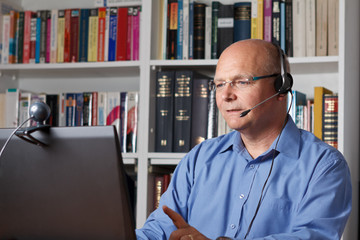 Mann mit Laptop, Headset und Kamera
