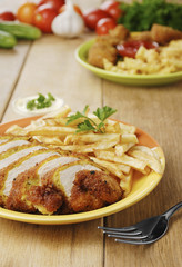 French fries and chicken on the plate on the wooden table