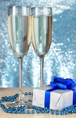 Naklejka na ściany i meble Glasses of champagne with gift box on shiny background