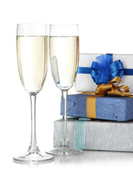 Glasses of champagne with gift boxes isolated on white