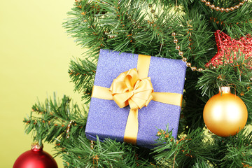 Fototapeta na wymiar Gift on Christmas tree on color background