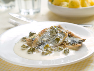 Fish fillet with lemon sauce and capers, selective focus