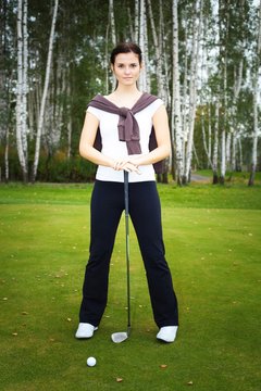 Woman golf player training on green with club