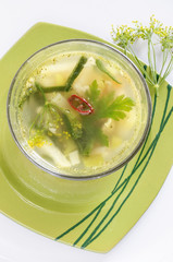 Vegetable soup in a glass bowl on green plate