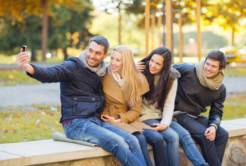group of friends with photo camera in autumn park