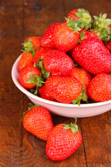 Fresh strawberry in bowl on wooden background