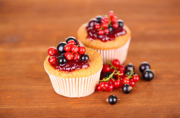 Tasty muffins with berries on wooden background