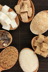 Different types of sugar in spoons on table close-up