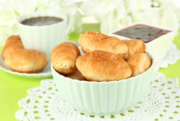 Tasty croissants and cup of coffee on table close-up