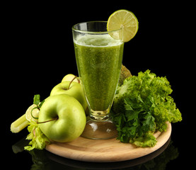 Glass of green vegetable juice and vegetables isolated on black