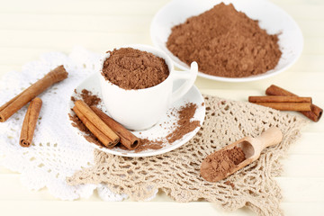Cocoa powder in cup on napkin on light background