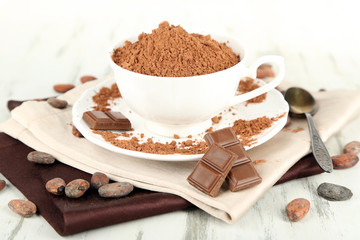 Cocoa powder in cup on napkin on wooden table