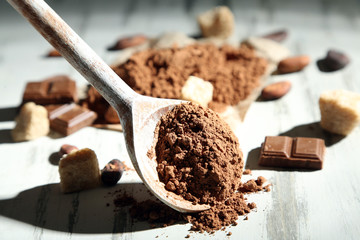 Cocoa powder in spoon on wooden table