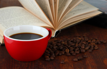 Cup of coffee with coffee beans and books on wooden background