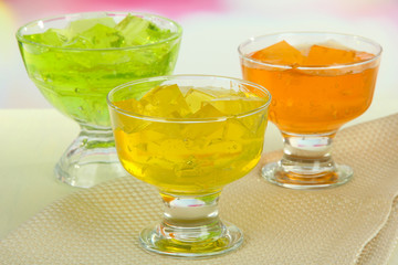 Tasty jelly cubes in bowls on table on light background