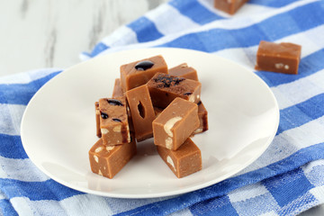 Many toffee on plate on napkin on wooden table