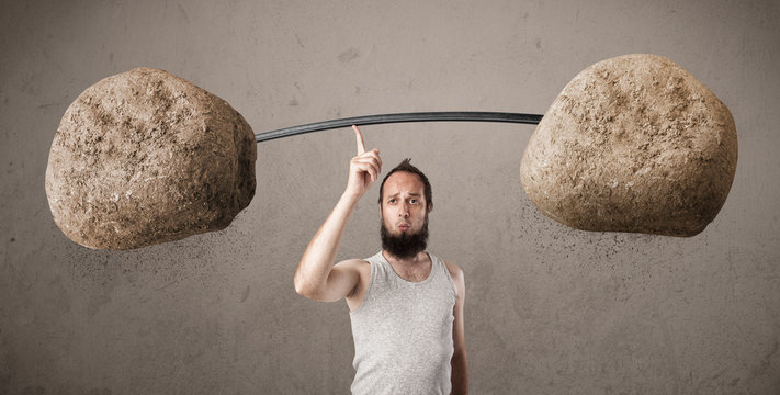 skinny guy lifting large rock stone weights