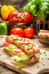 Homemade hot dog with two sausages and vegetables