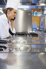 Young gorgeous chef standing next to work surface phoning