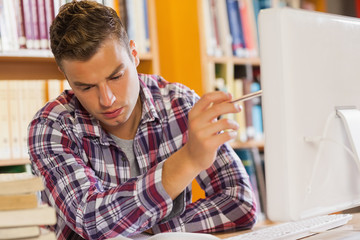 Handsome serious student pointing at computer