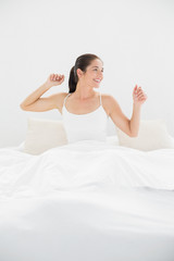 Smiling woman stretching her arms in bed