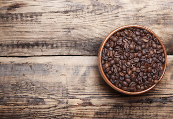 Coffee beans in wooden bowl on wooden background.