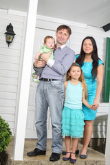 Happy young family stand on porch of new their cottage.