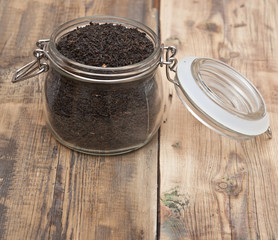 black tea in glass jar on old wooden table