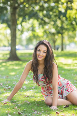 Fototapeta premium Stylish cheerful brunette sitting on grass