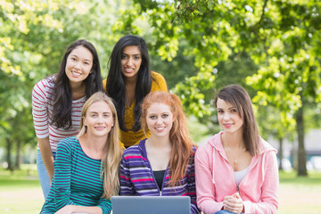 Fototapeta na wymiar Portrait of college girls with laptop in park