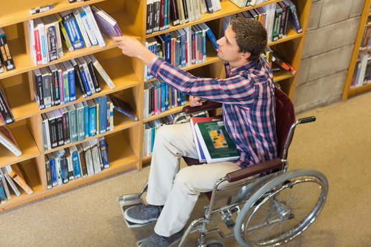 Man in wheelchair selecting book in the library