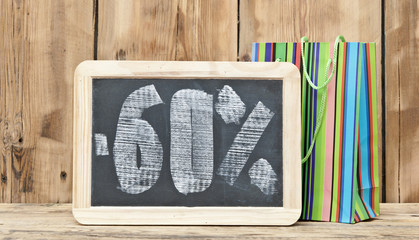 sixty percent discount written on blackboard with colorful shopi