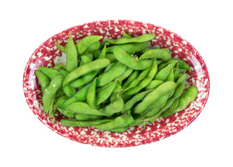 Cooked edamame pods in a red serving dish