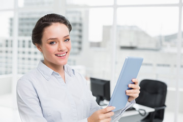 Smiling young businesswoman using table PC in office