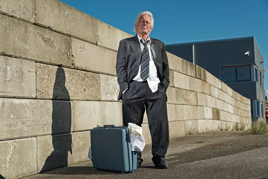 Depressed senior business man with suitcase without a job and ho