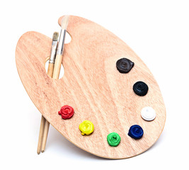 wooden art palette with paint and brushes isolated on white