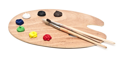 wooden art palette with paint and brushes isolated on white