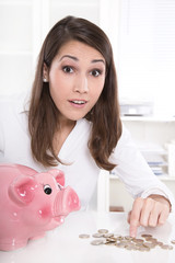Obraz na płótnie Canvas Junge Frau im Büro mit Sparschwein und Geld - Konzept