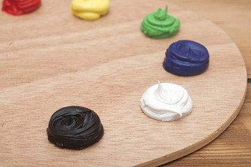 Oil paint on a palette sitting on a wood background. Focus on wh