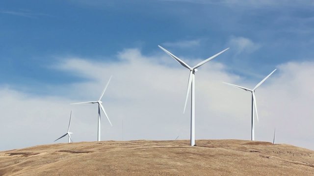 Four large wind turbines on top of a hill
