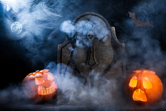 Halloween foggy night with pumpkins, tombstone,moon and bat.